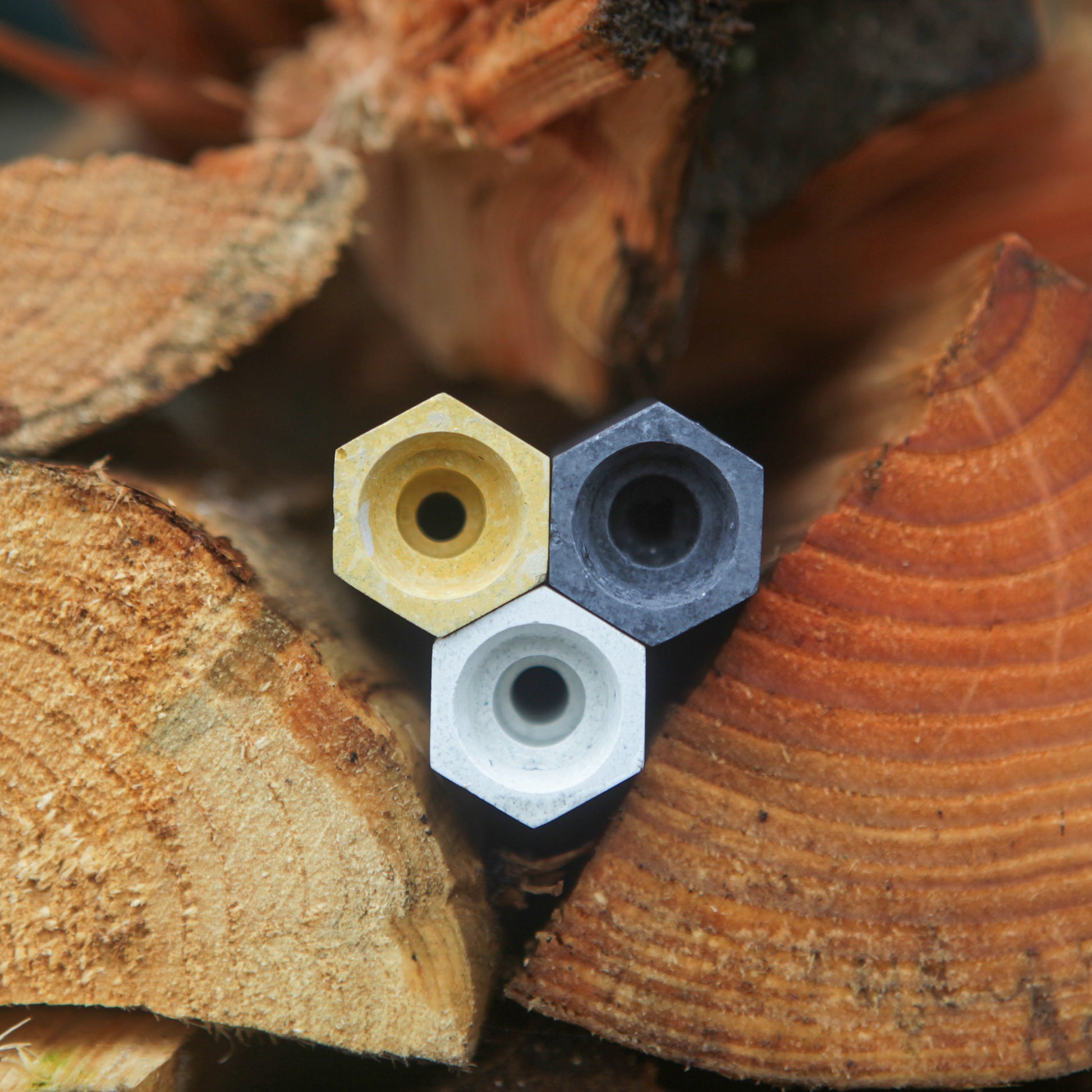 Three small, single cell, hexagonal bee cells for solitary bees stacked together amongst some logs.