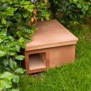 Hedgehog nest box placed under hedging. Made of FSC certified plywood.