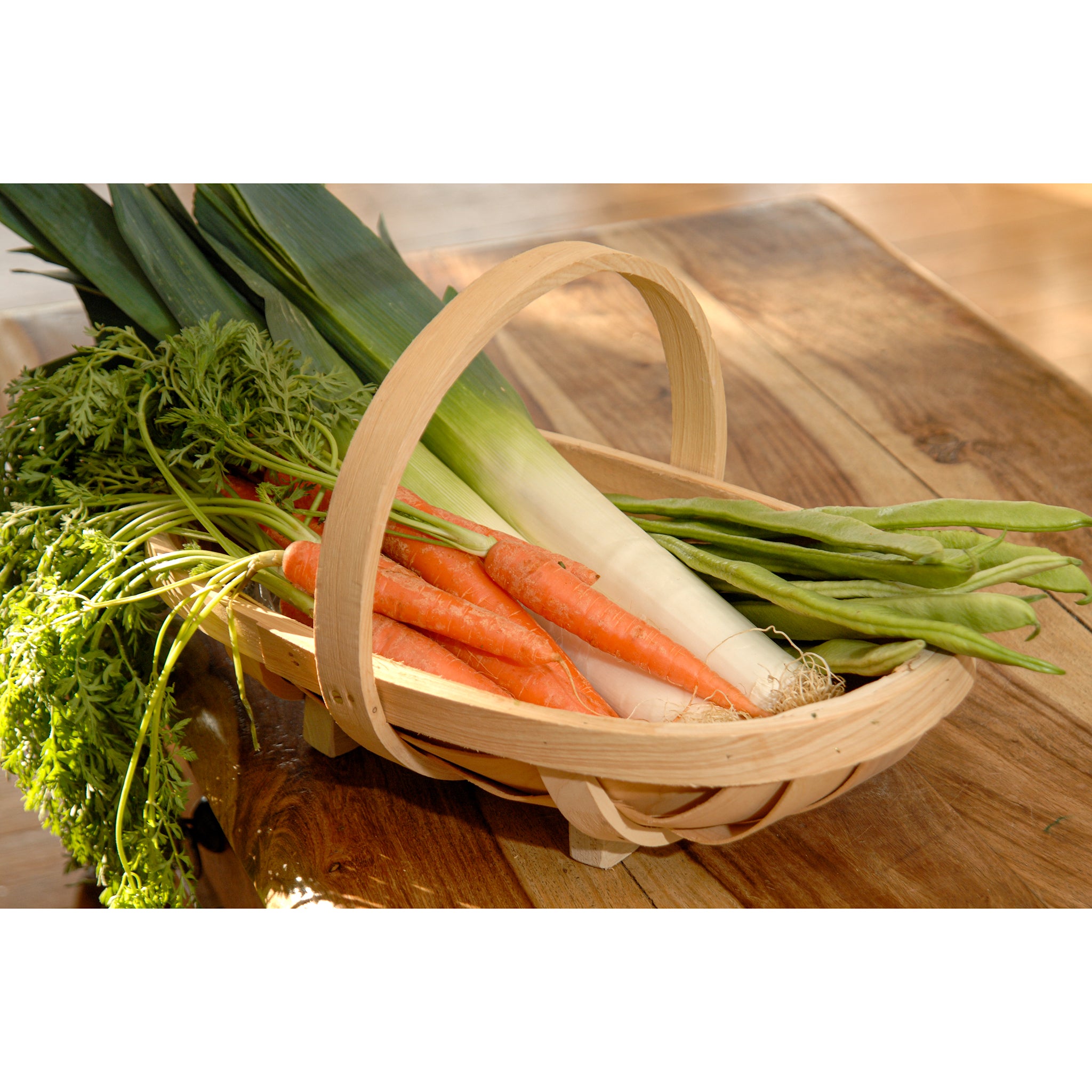 Wooden garden trug in a medium size full of vegetables and placed on a kitchen table.